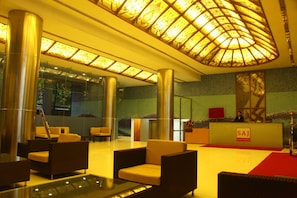 A lobby with a reception desk, seating area, and a large glass wall. - Saj Luciya (Thiruvananthapuram)