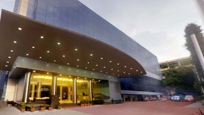 A modern building with a curved entrance, glass facade, and a covered area with lights. - Saj Luciya (Thiruvananthapuram)