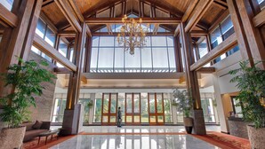 A spacious lobby with a high ceiling, large windows, and a chandelier.