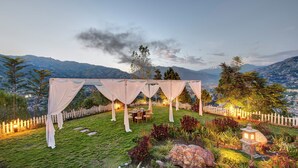 A tented outdoor dining area with a view of mountains and a white picket fence.