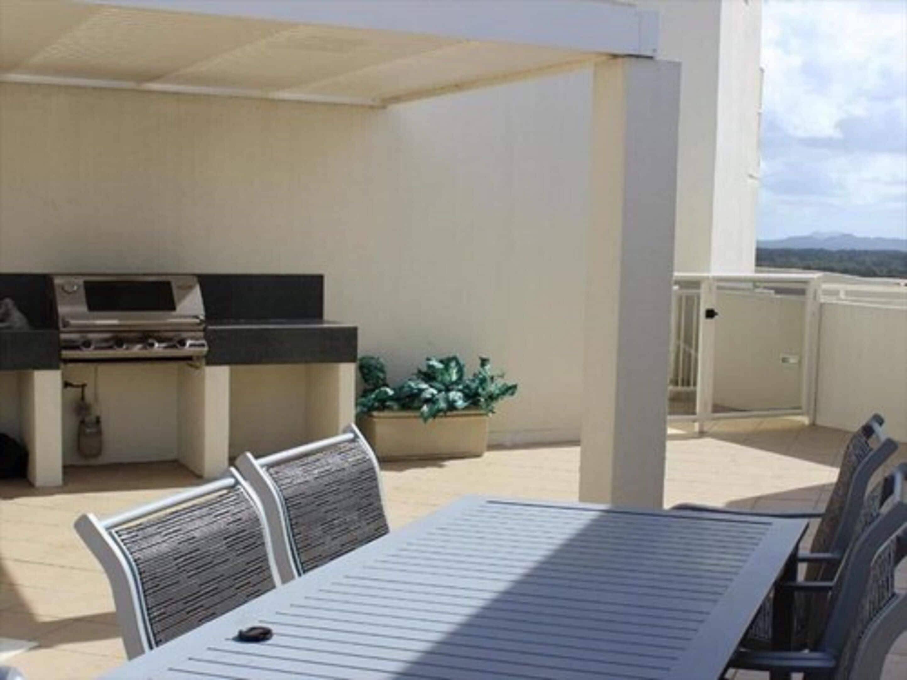 Patio esterno con barbecue, zona salotto e piante in vaso.