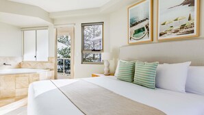 A hotel room with a large bed, a bathroom with a bathtub, and a balcony with a view of trees. - Mantra Zanzibar (Mooloolaba)