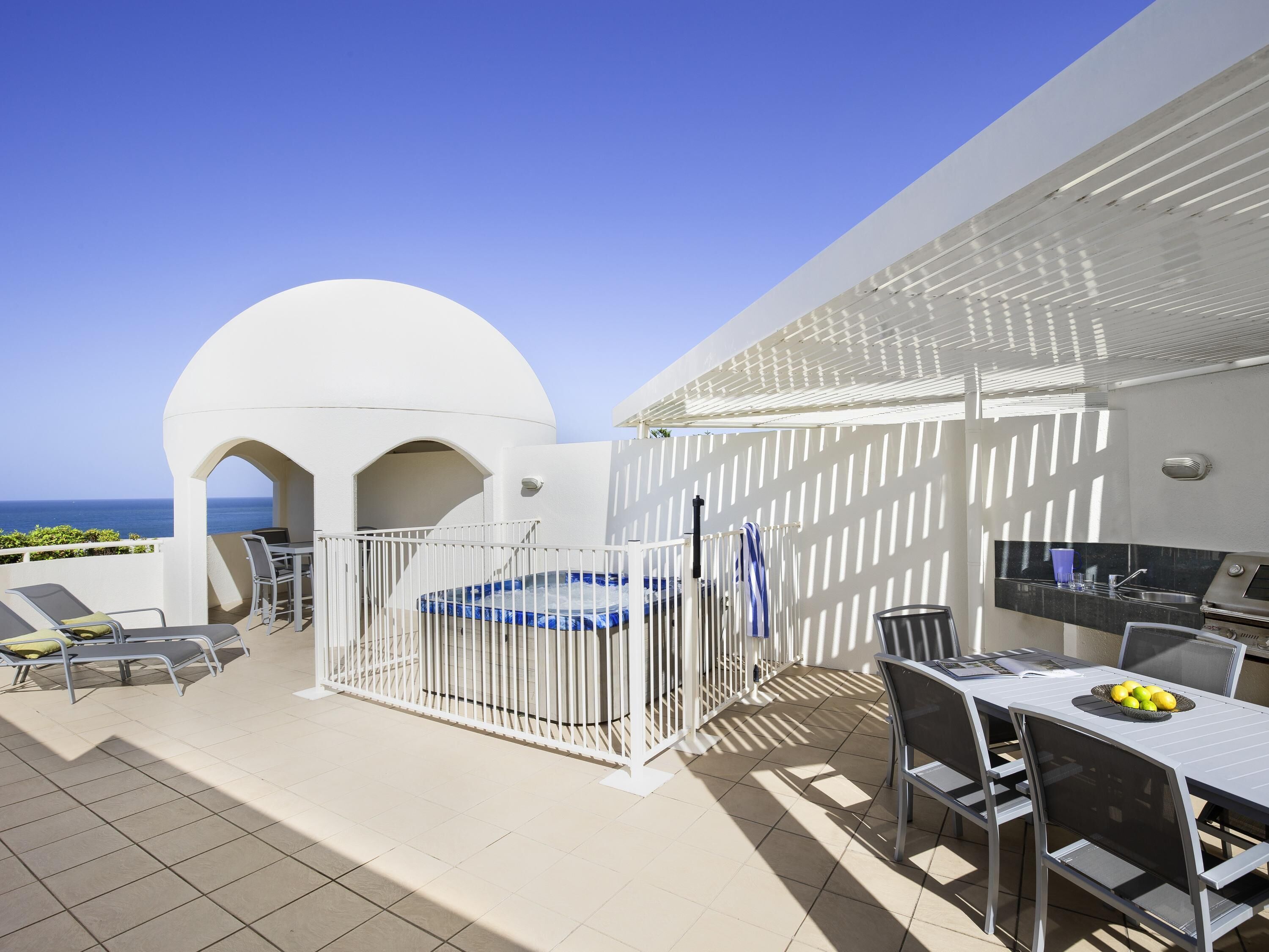 Eine Terrasse mit Pool, Liegestühlen, Essbereich und Meerblick.