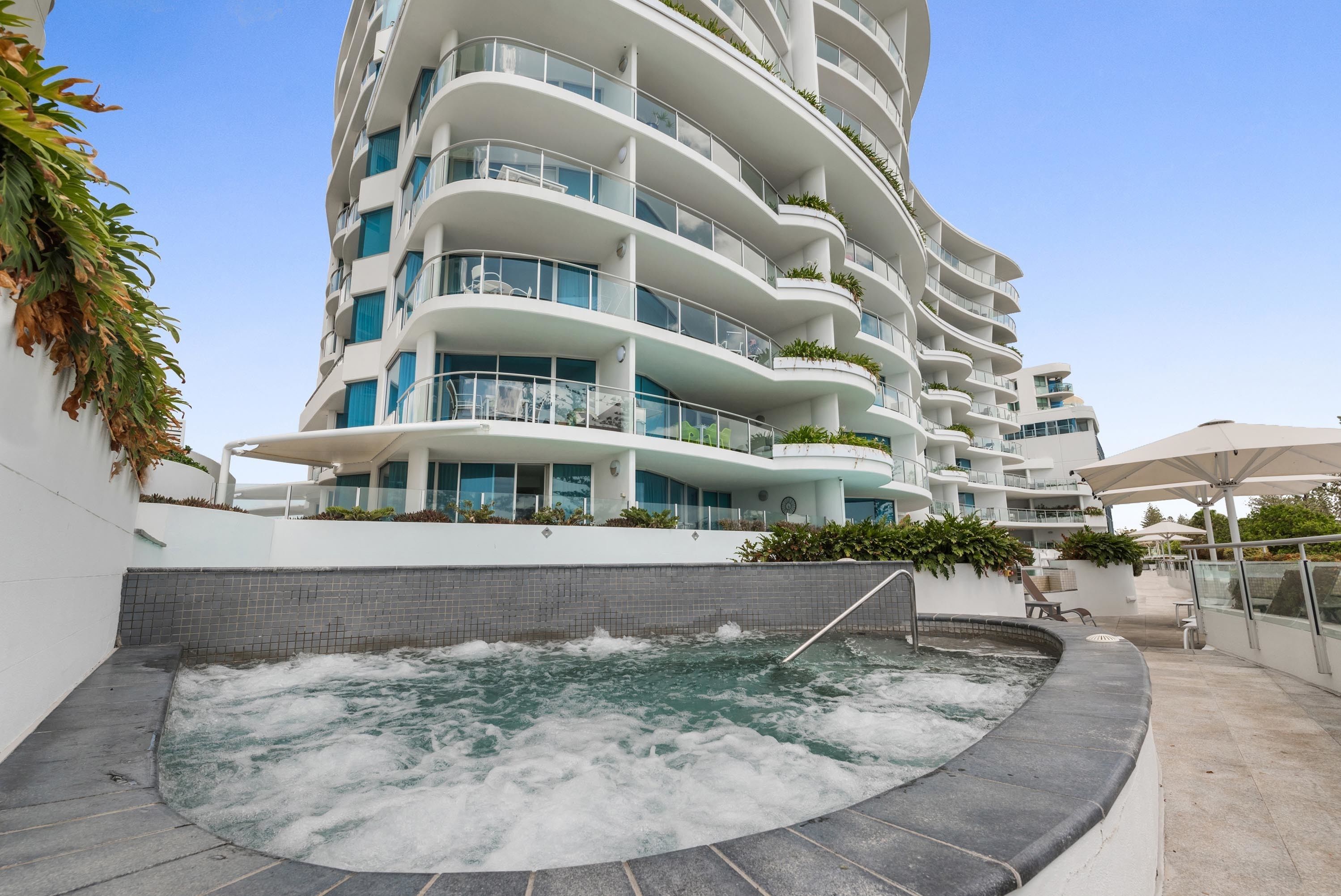 A modern hotel with a spa area featuring a hot tub, outdoor seating, and a pool.