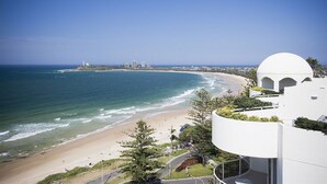 A coastal view with a beach, ocean, and a modern building with a dome structure. - Mantra Sirocco Resort (Mooloolaba)