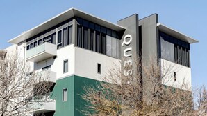 A modern building with a flat roof, large windows, and a prominent vertical sign.