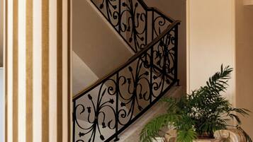 A marble staircase with a wrought iron railing and a large decorative urn with a plant.