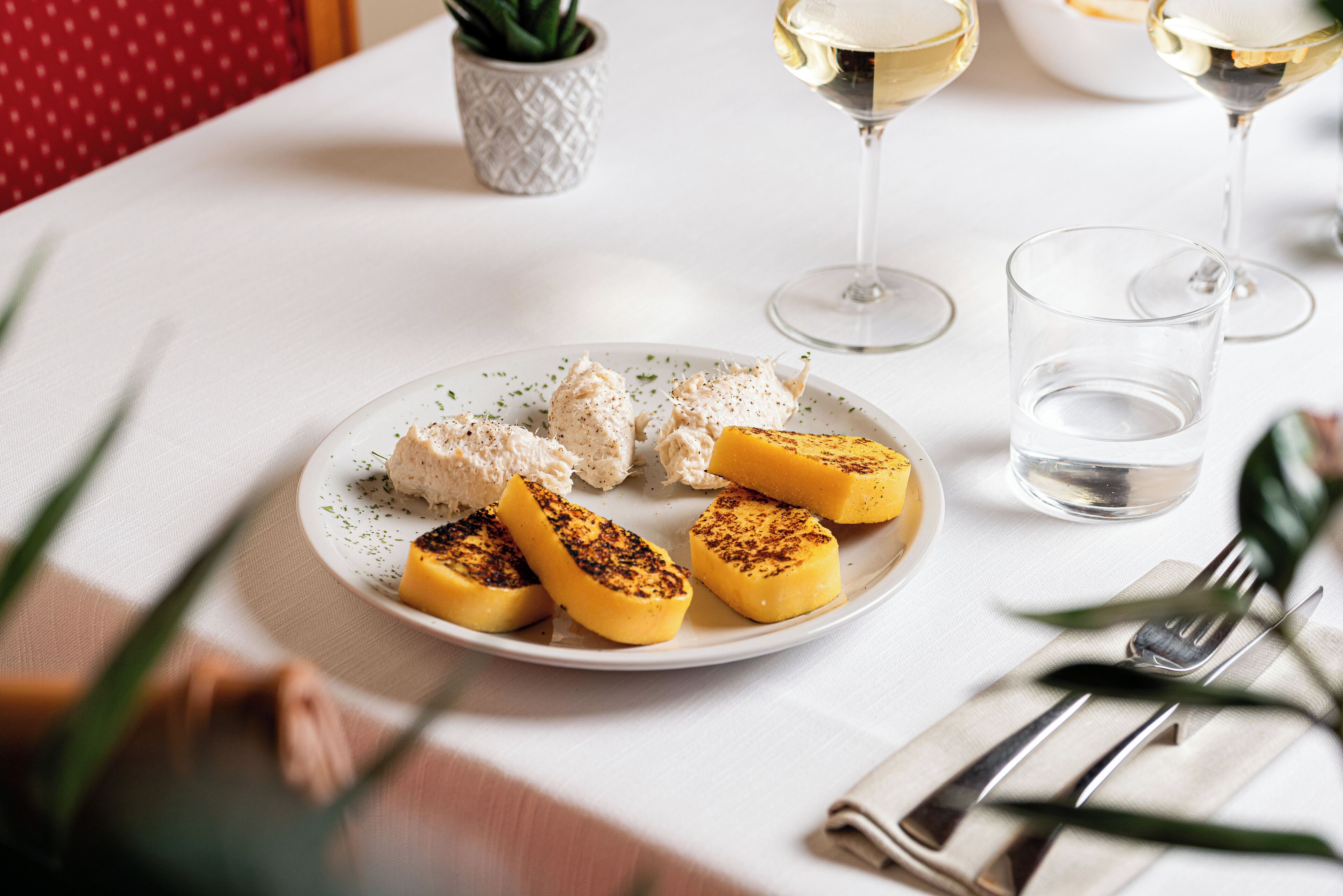 Ein Teller gegrilltes Hähnchen und Bananenscheiben auf einer weißen Tischdecke.