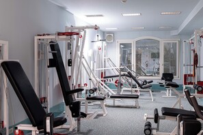 A gym with various exercise machines, a large mirror, and a window with a view of the outside.