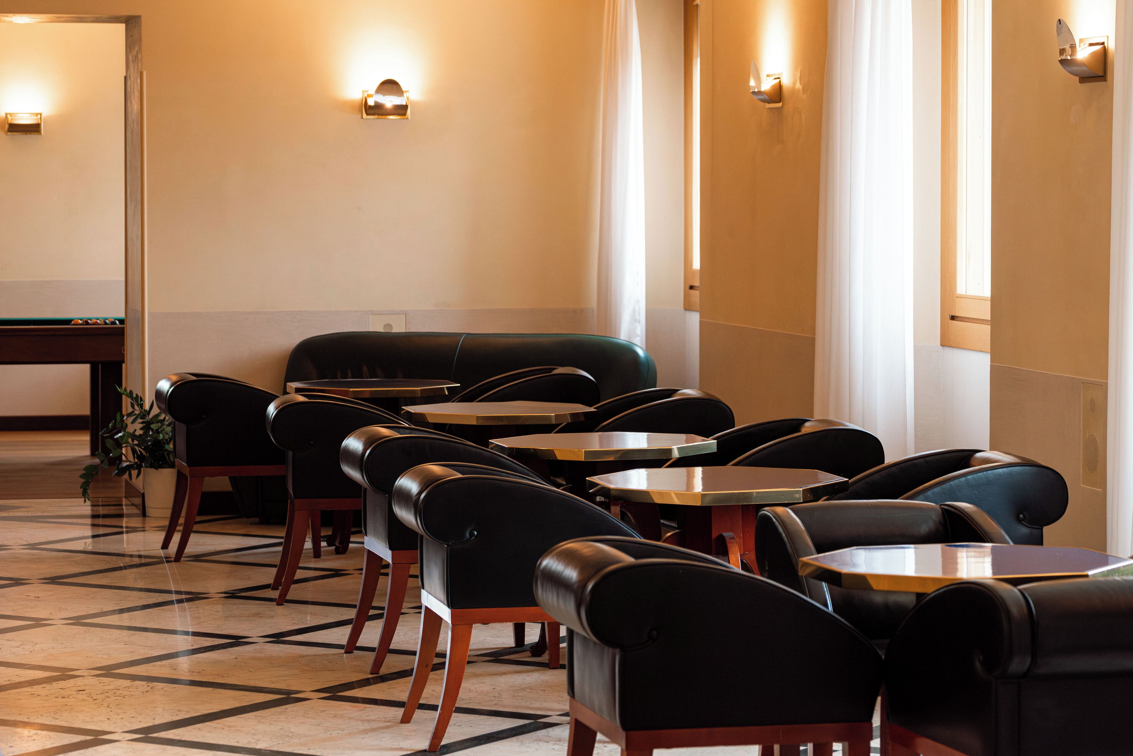 Una sala de billar con varias mesas y sillas, una mesa de billar y luces fijadas a la pared.