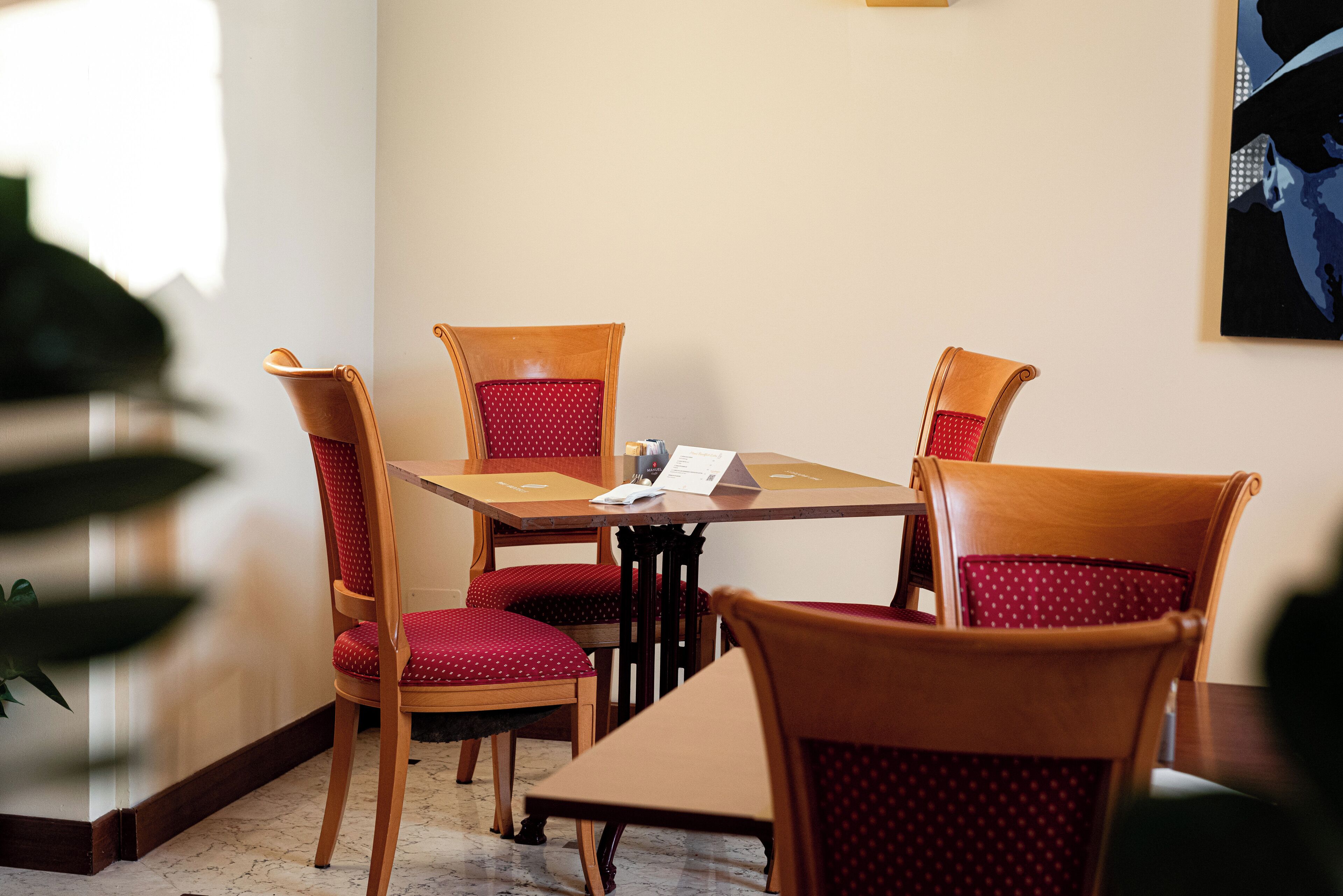 Un salón de conferencias con una mesa de madera y cuatro sillas con cojines rojos.