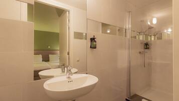 Een moderne badkamer met een wastafel, spiegel en douche.
