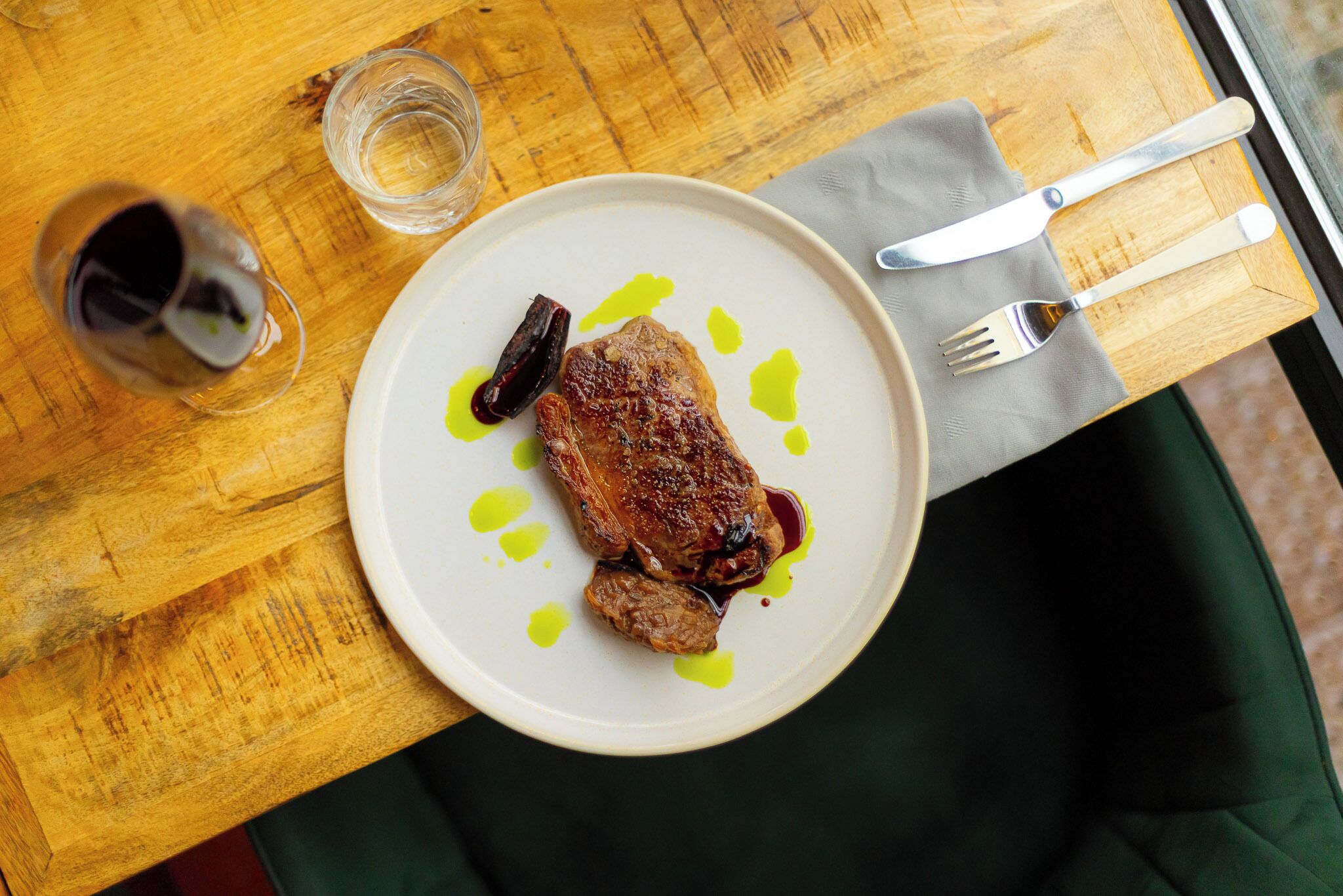 Ein Teller mit einem Steak und Sauce auf einem Holztisch.