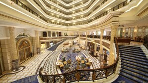 A grand hotel lobby with a central circular seating area, multiple staircases, and ornate columns. - Legendale Hotel Beijing (Beijing)