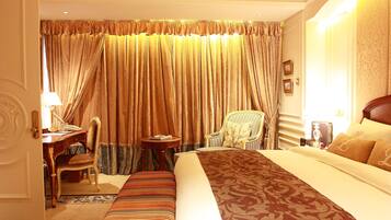 A hotel room with a large bed, a desk, a chair, and a small table.