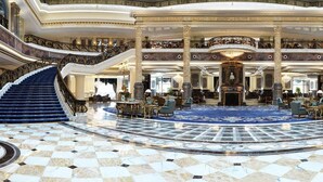 A grand lobby with a central fountain, multiple staircases, and a checkered marble floor. - Legendale Hotel Beijing (Beijing)