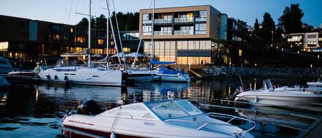 A marina with boats docked, a modern building with large windows, and a clear sky.