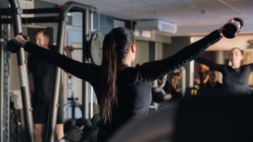 Un gimnasio con equipo de ejercicio y personas entrenando.