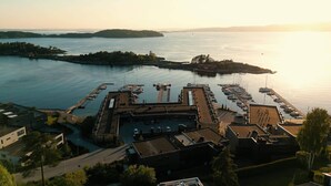 A marina with boats docked, a parking area, and buildings with flat roofs.