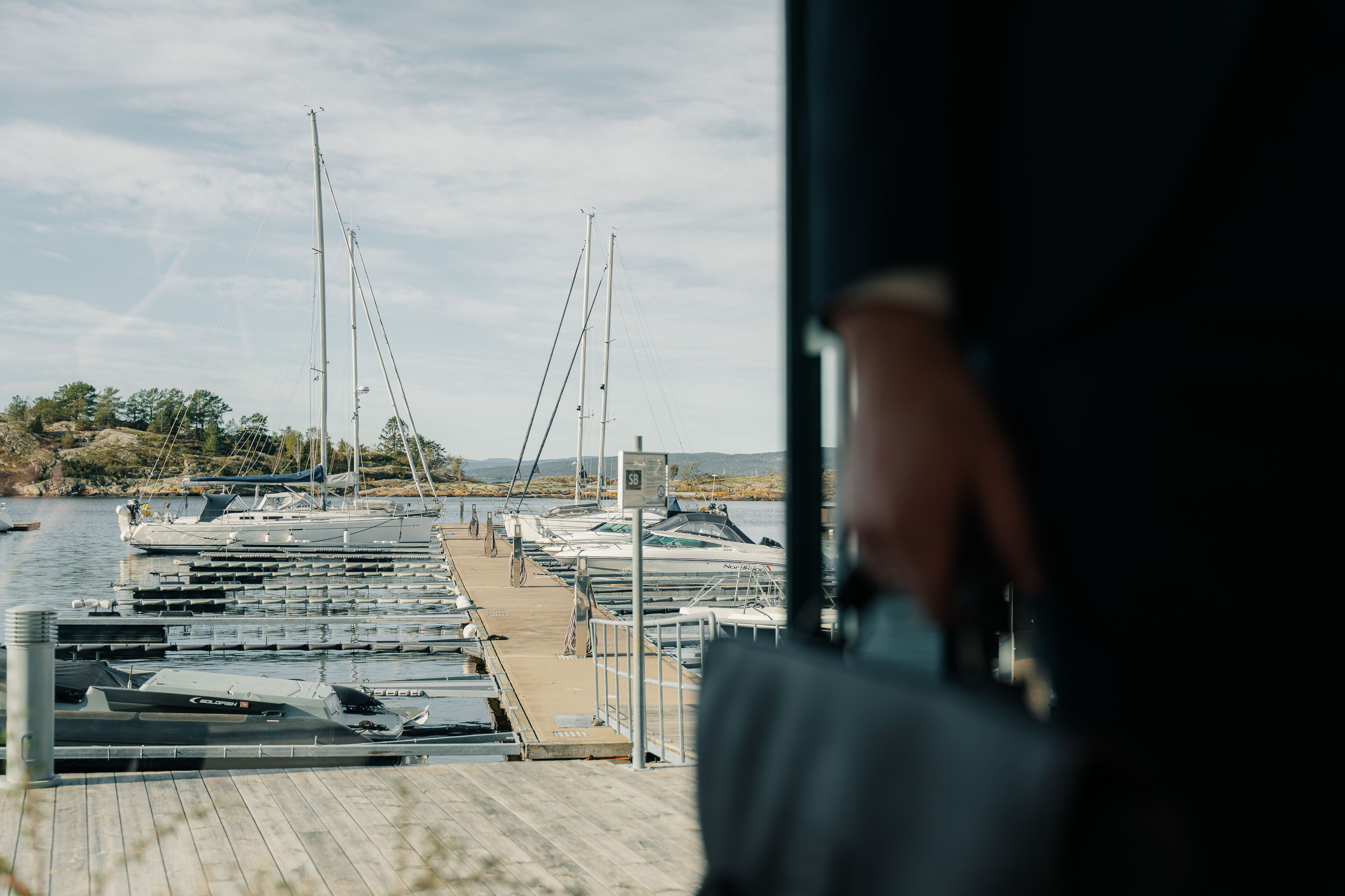 A marina with several boats docked, a wooden pier, and a clear sky.