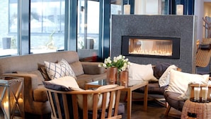 A modern living room with a fireplace, a sofa, a coffee table, and a chair.