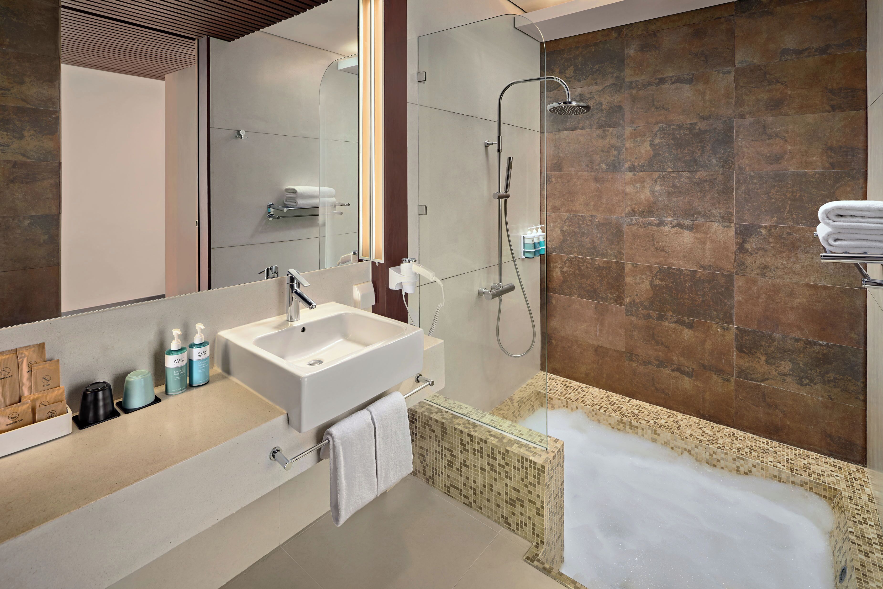 Un baño moderno con un espejo grande, un lavamanos, ducha y bañera.