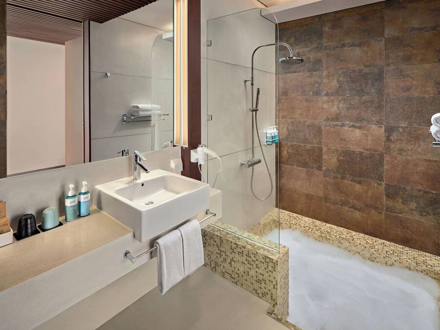 Un baño moderno con un espejo grande, un lavamanos, ducha y bañera.