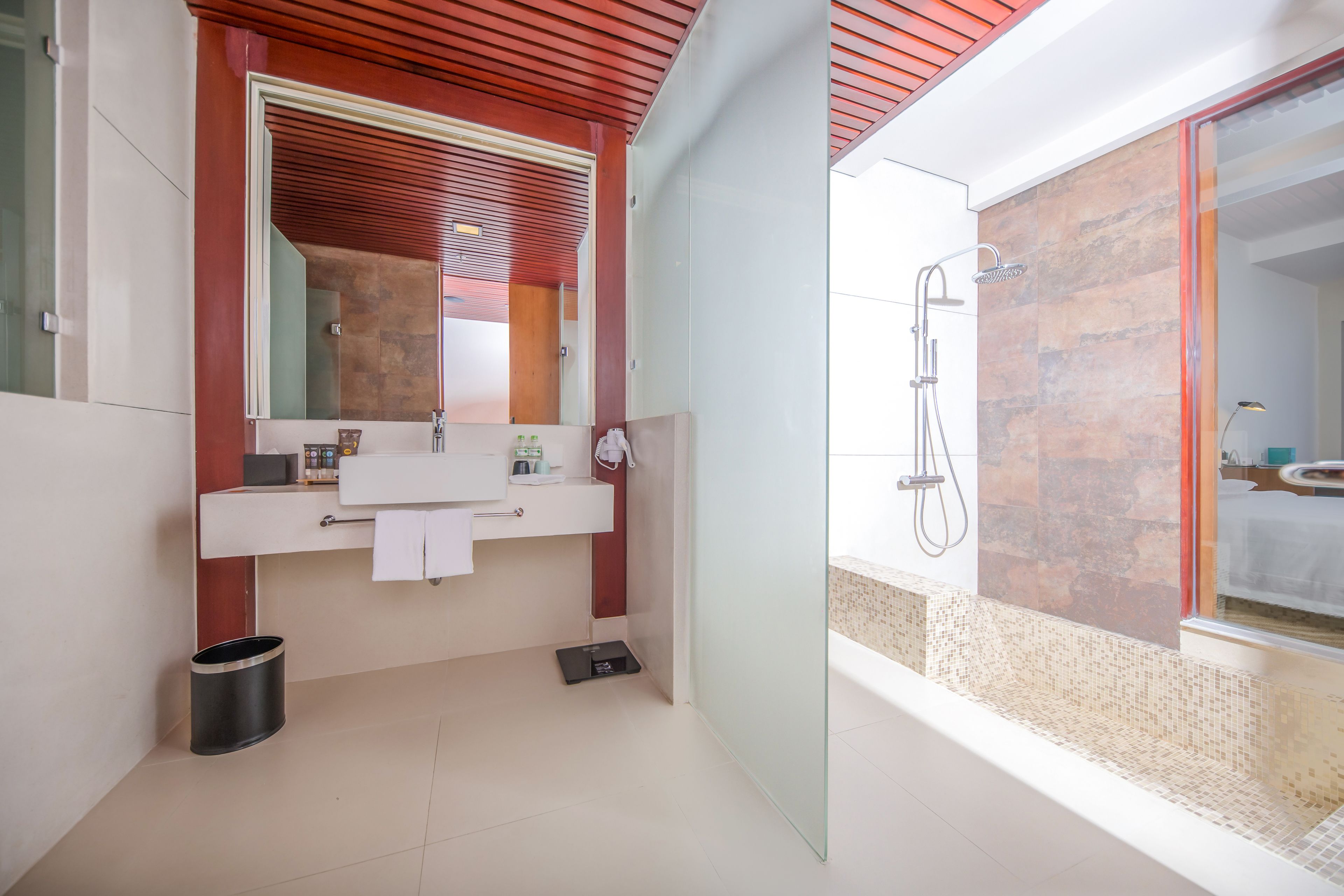Un baño moderno con cabina de ducha de vidrio, un lavamanos blanco y un espejo.