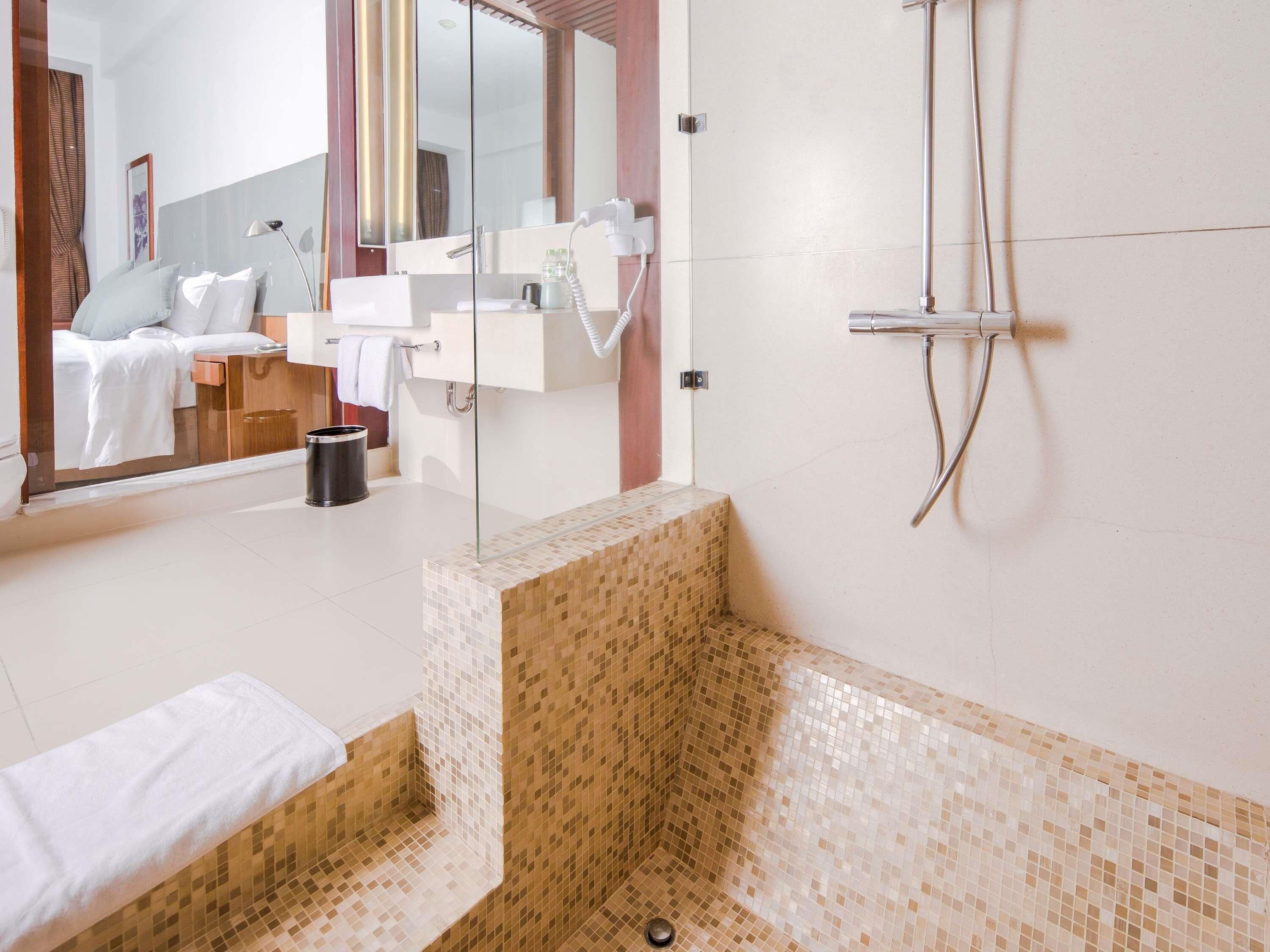 Un baño moderno con cabina de ducha de vidrio, un lavabo blanco y un espejo grande.