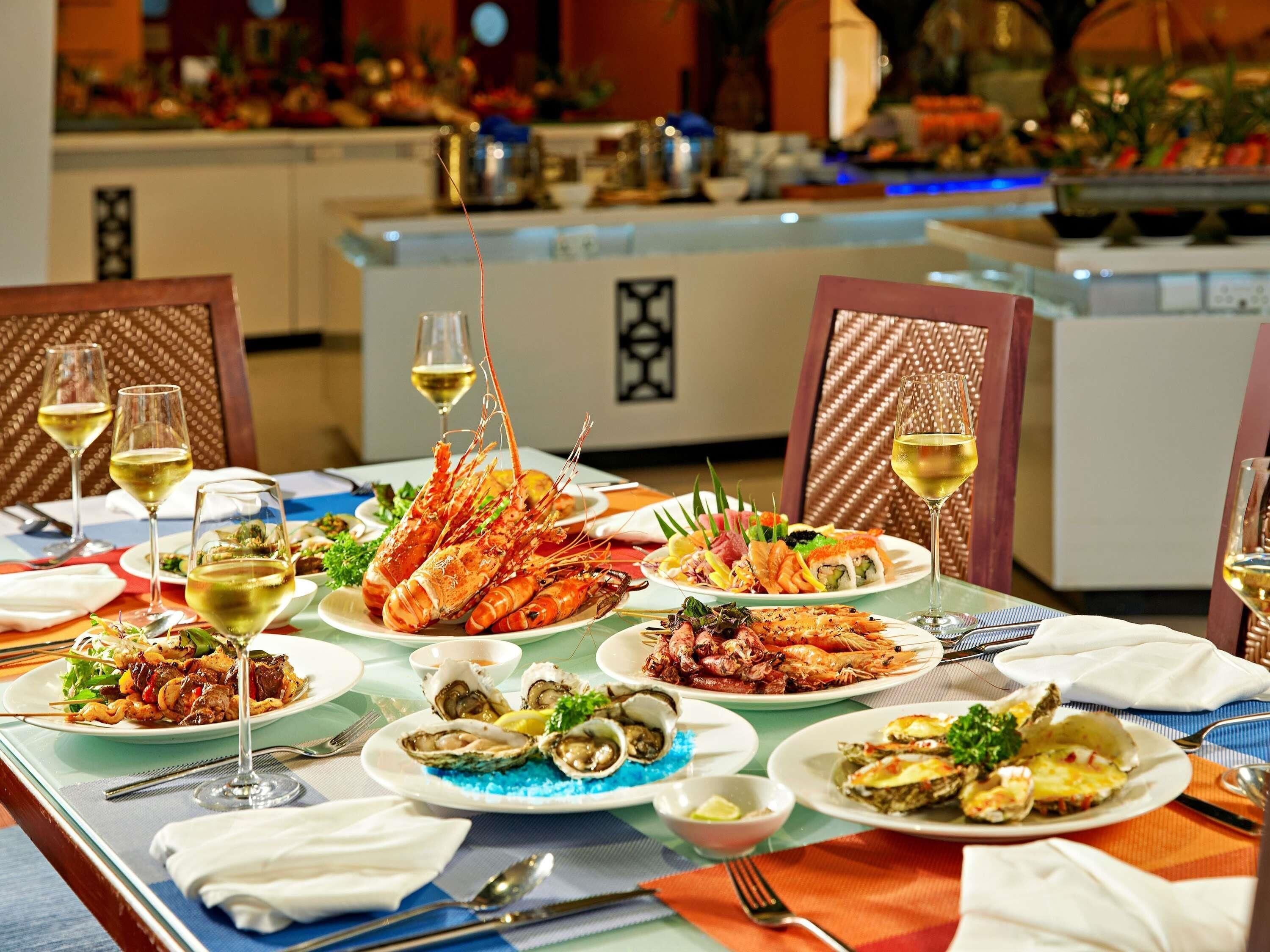Une table à manger dressée avec des plats de fruits de mer, des verres à vin et des couverts.