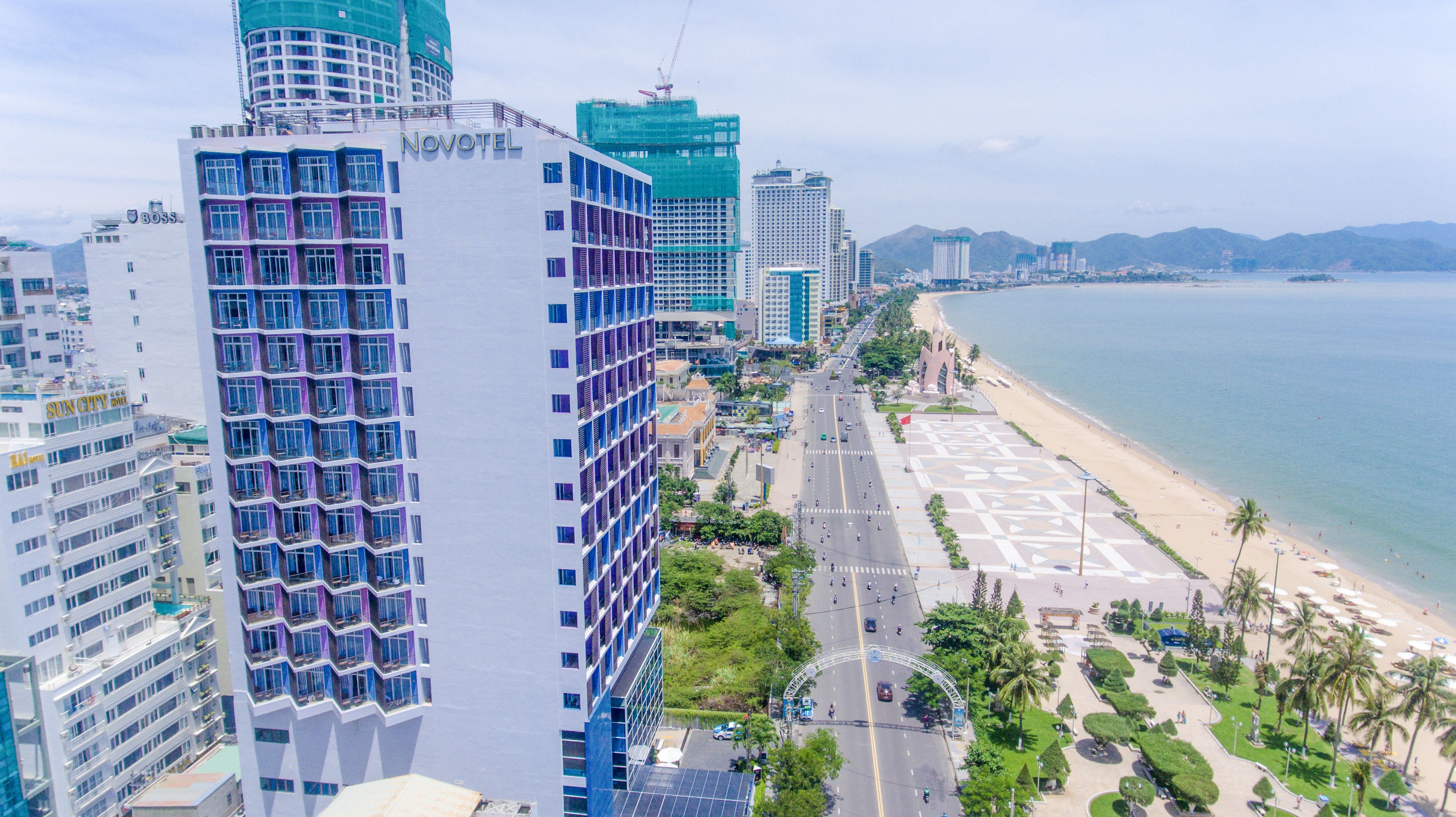 A high-rise hotel with multiple floors, a beachside promenade, and a view of the ocean.