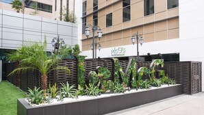 A modern building with a McGills by McGREGG'S sign, featuring a landscaped garden with palm trees and various plants.