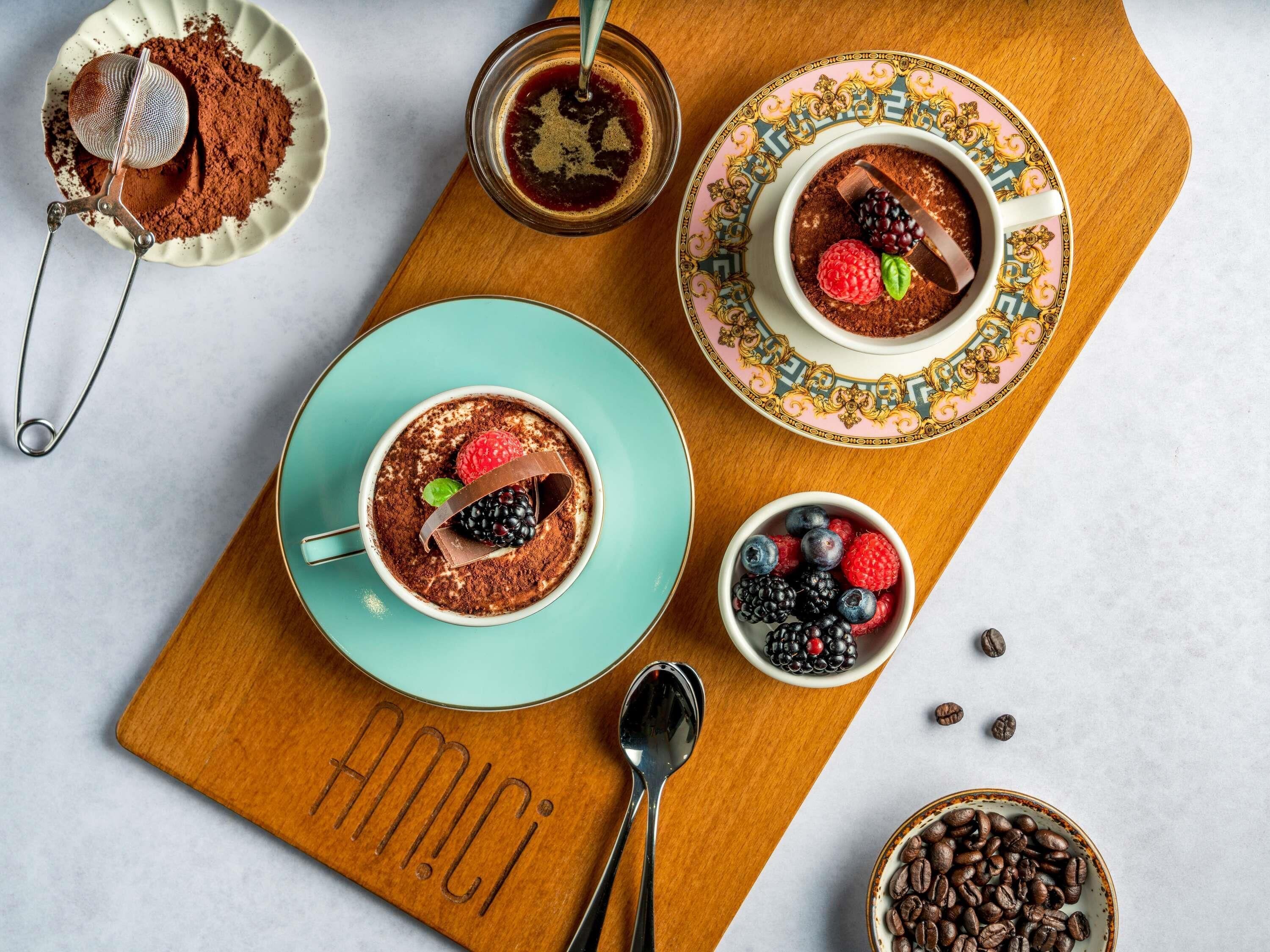 Ein Dessert-Arrangement mit Schokoladenmousse, Beeren und Kaffeebohnen auf einer Holzbrett.