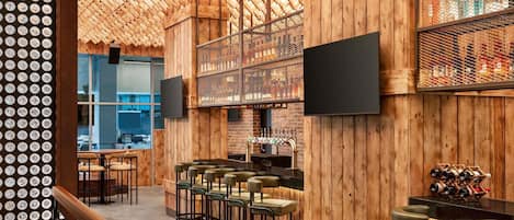 A bar area with wooden walls, multiple seating arrangements, and a television mounted on the wall.