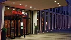 Entrada del Hotel InterCity con puerta de cristal, una pantalla digital y un alero curvo.