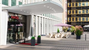 Entrada del Hotel InterCity con puerta de vidrio, zona de estar al aire libre y plantas en macetas.