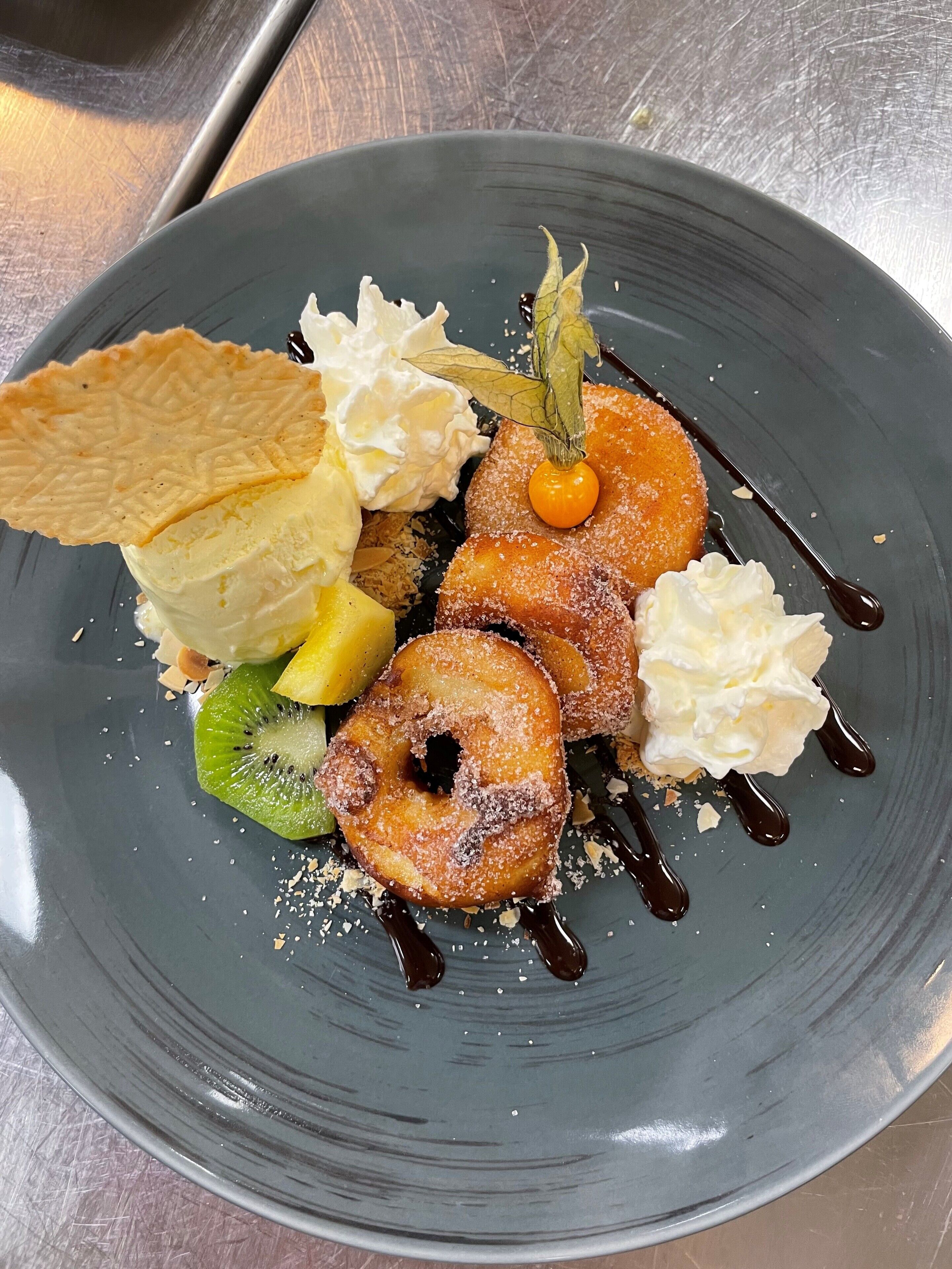 A dessert plate with various items including a pastry, whipped cream, and a fruit slice.