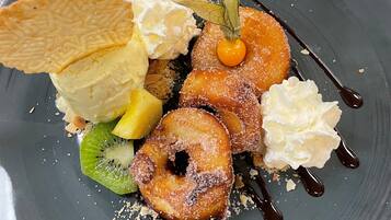 A dessert plate with various items including a pastry, whipped cream, and a fruit slice.