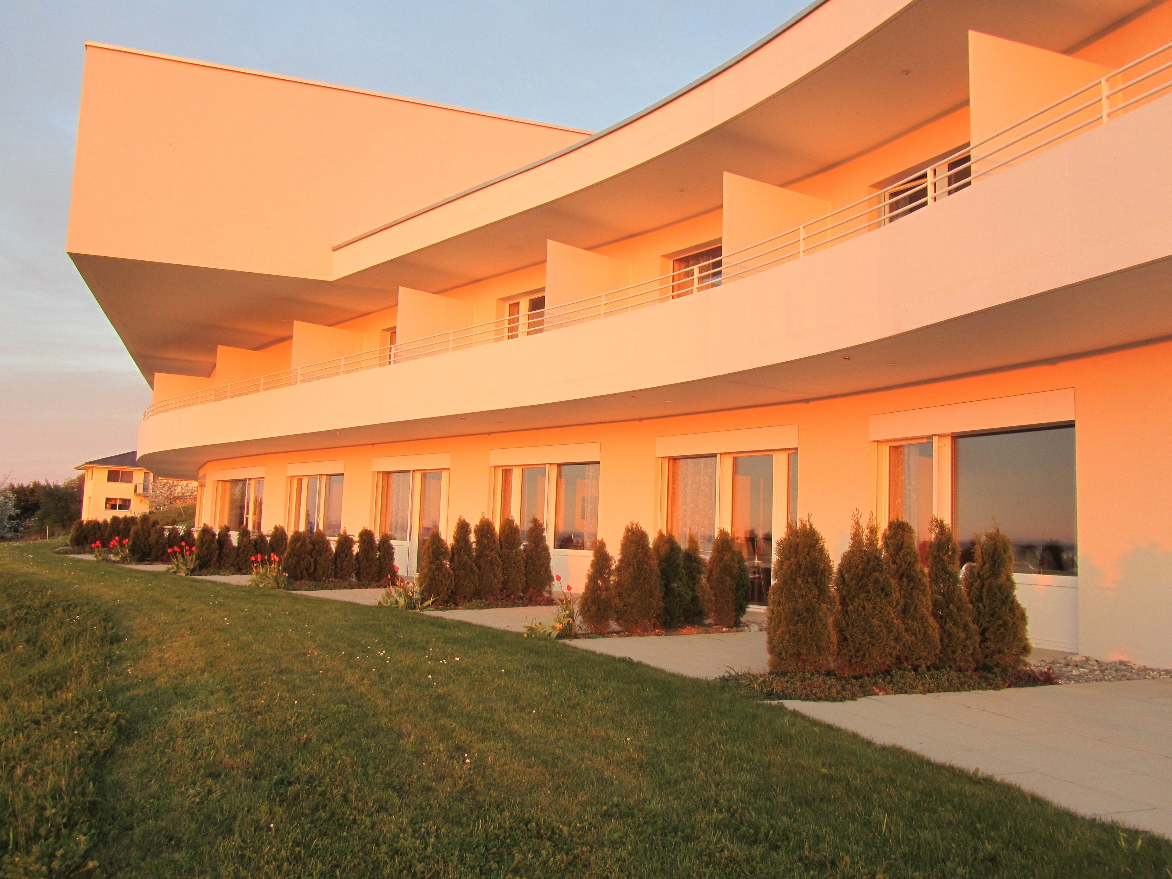 A modern multi-story building with a flat roof and large windows.