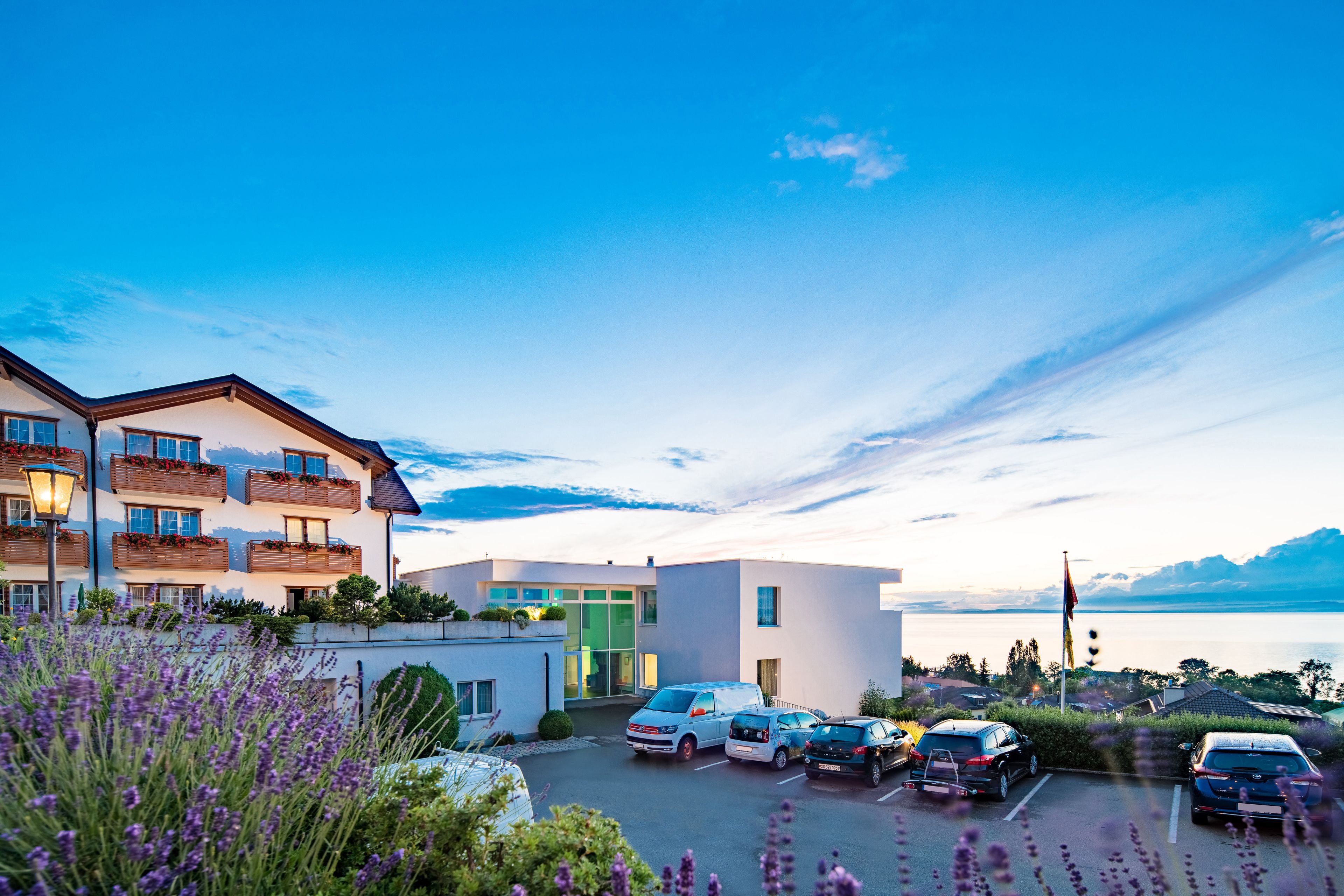 A hotel with a parking lot, a building with balconies, and a view of the water.