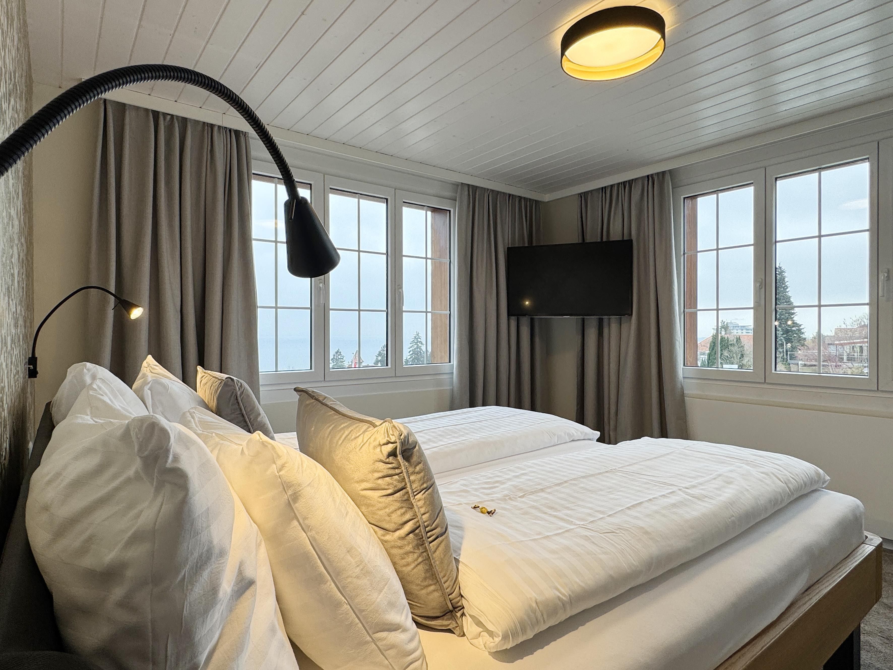 A hotel room with a bed, a TV, and a window with curtains.