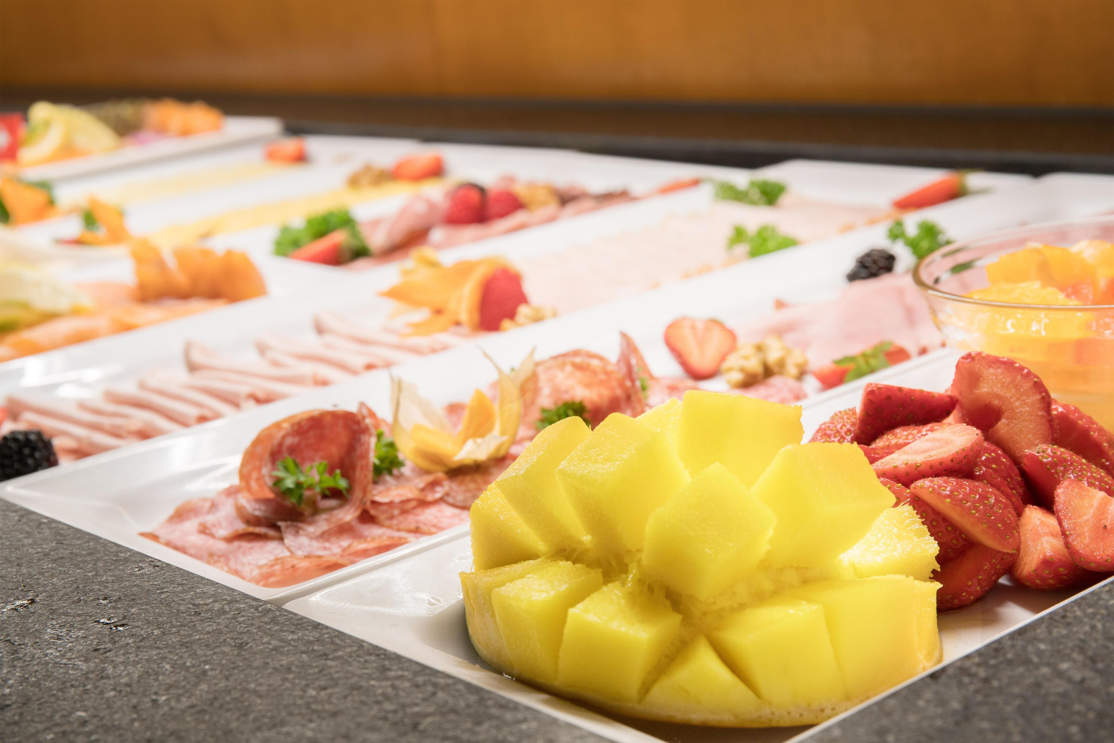 A buffet with various food items including fruits and meats.
