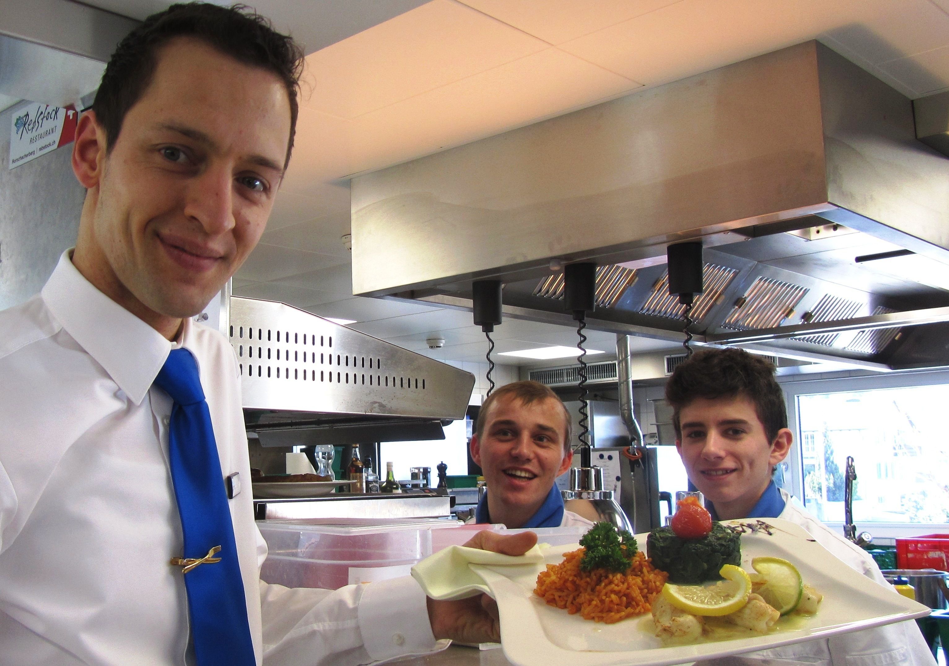 Una persona sosteniendo un plato con comida, una campana extractora en la cocina y una ventana al fondo.