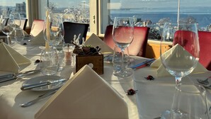 Mesa de comedor dispuesta con cristalería, cubiertos y una vela, con vistas a un paisaje panorámico.