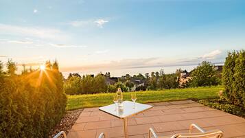 An outdoor patio with a table and chairs, a bottle of wine, and a glass.
