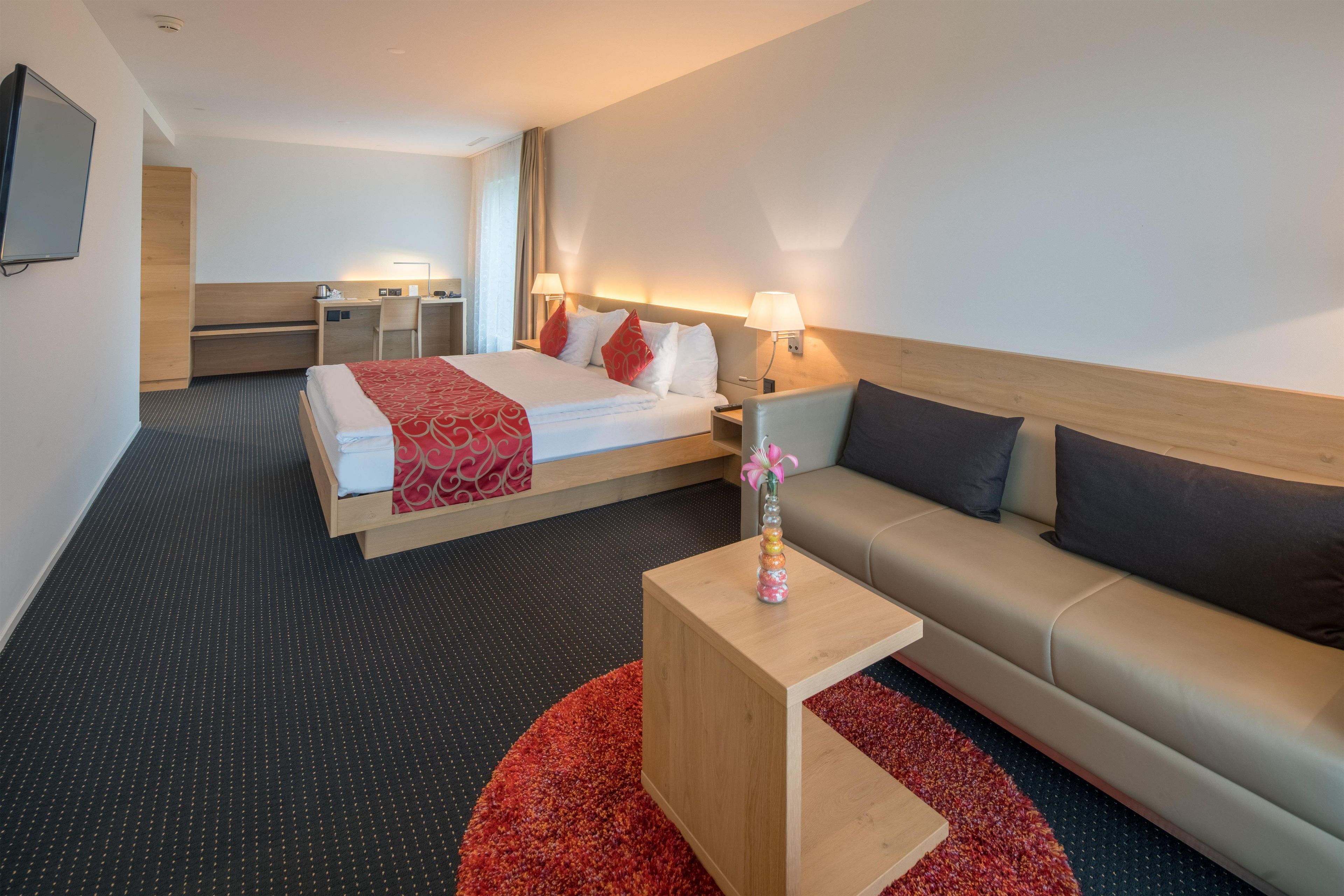 Habitación de hotel con cama, sofá, escritorio y televisión.