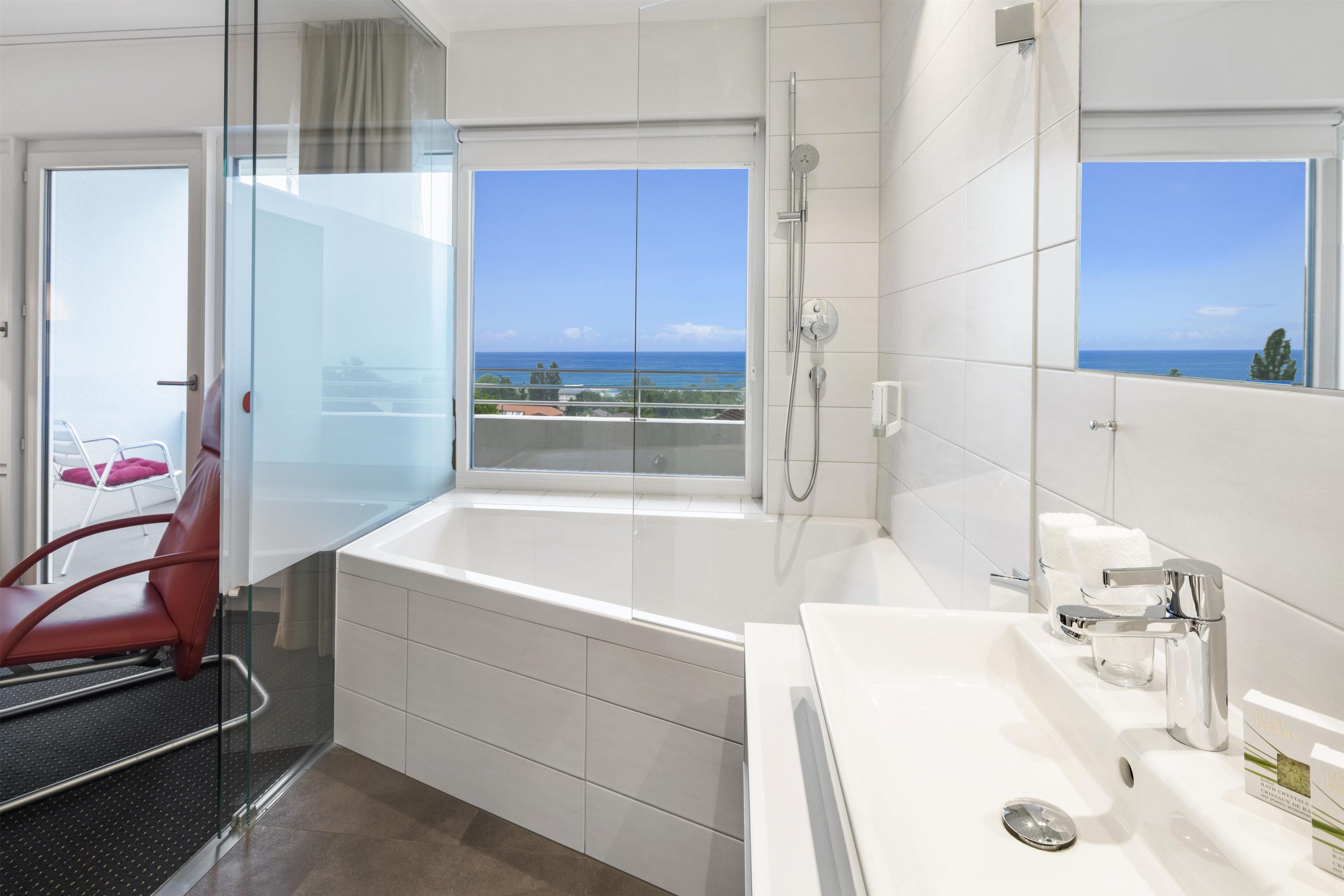 Un baño moderno con bañera, ducha y un amplio ventanal con vistas al océano.