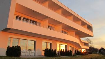Un edificio moderno de varios pisos con balcones, ventanas amplias y un césped cuidado.