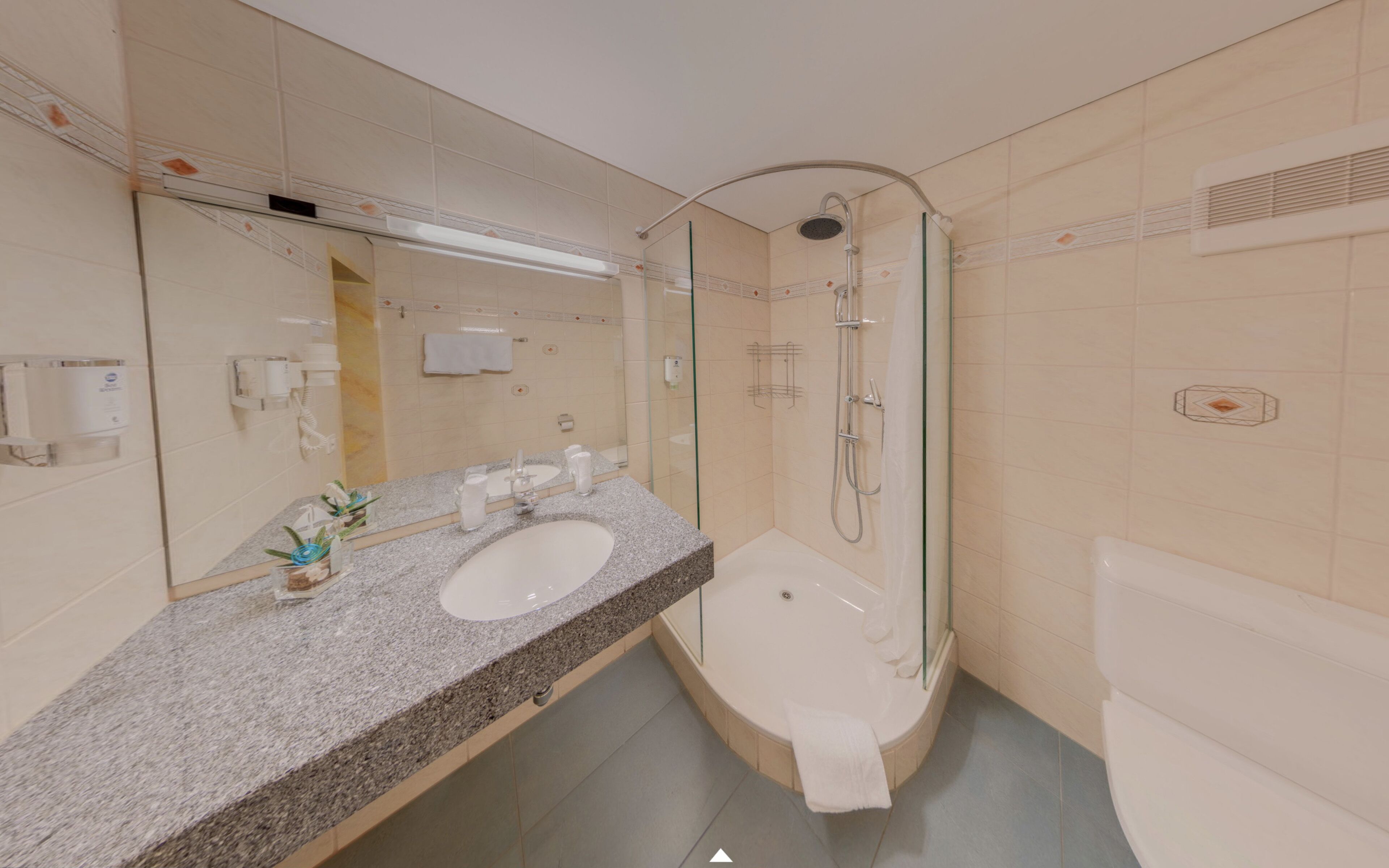 A modern bathroom with a granite countertop, a large mirror, a bathtub, and a glass-enclosed shower.