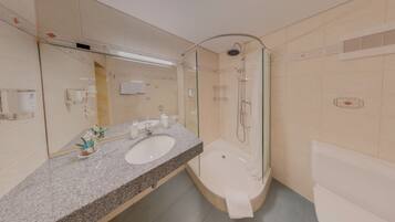 Un baño moderno con encimera de granito, un espejo grande, una bañera y una ducha con mampara de vidrio.